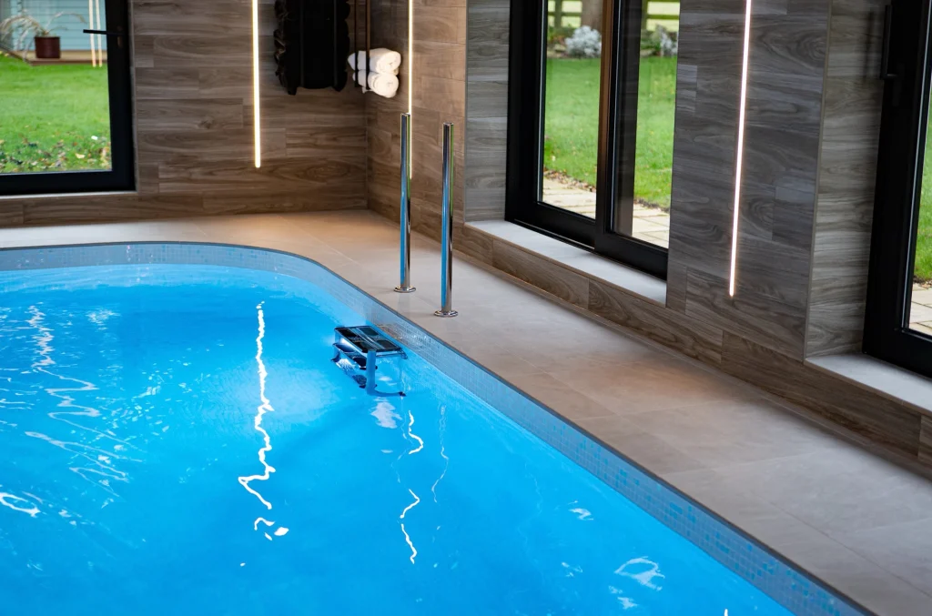 Modern indoor swimming pool with wood-panelled walls and garden views