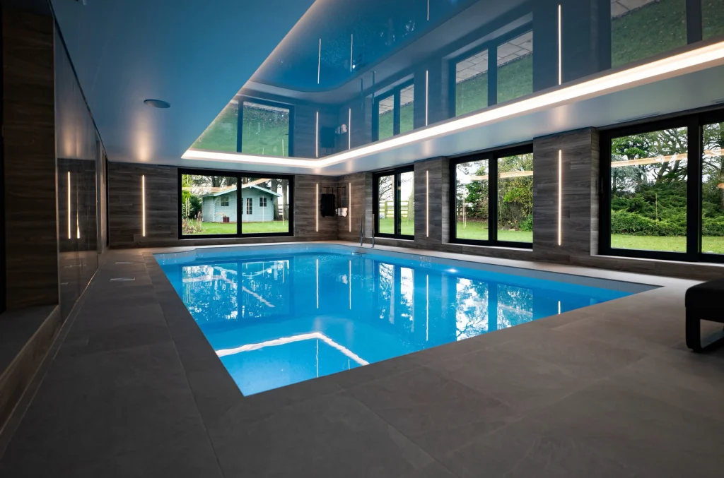 Modern indoor swimming pool with blue water and glass walls