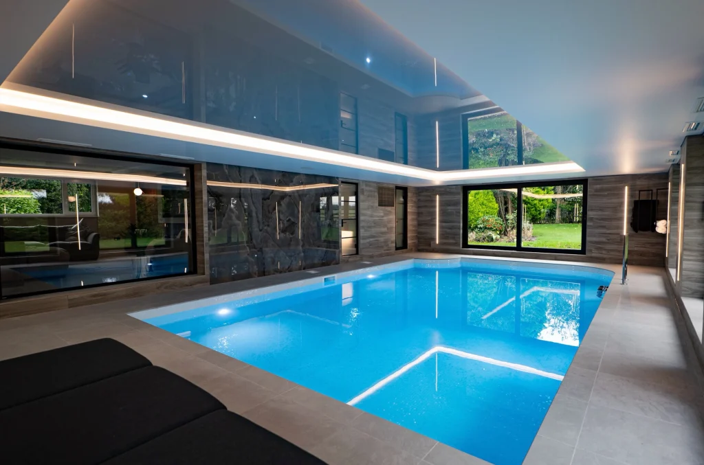 Modern indoor swimming pool with blue water and glass walls