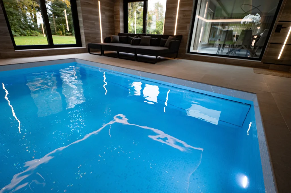 Indoor swimming pool with modern lounge area and natural light
