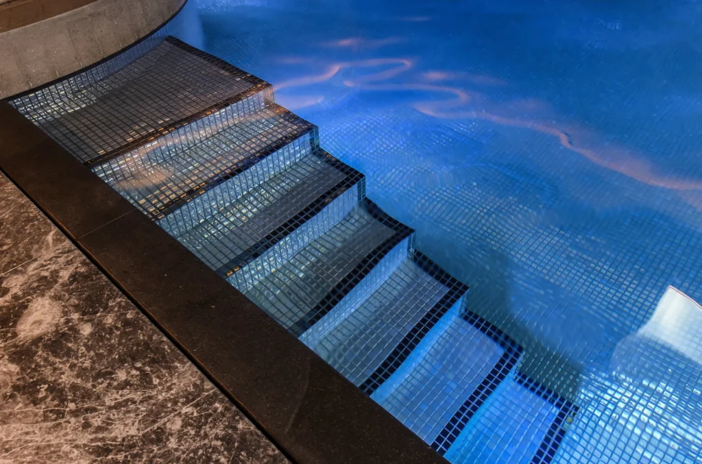 Metal mesh pool steps descending into bright blue water