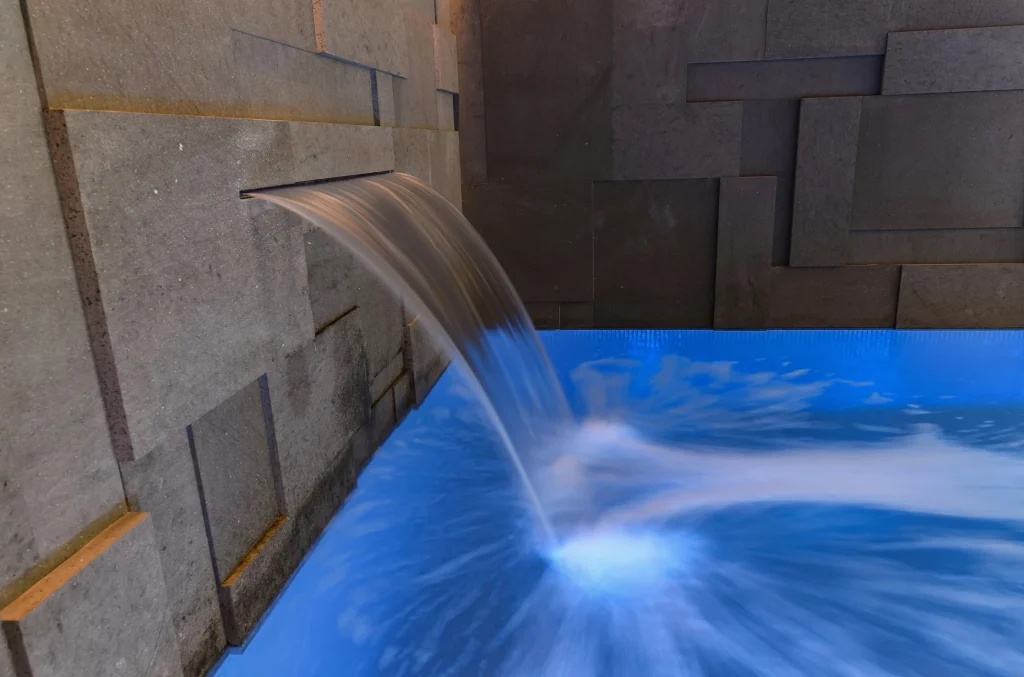 Water cascading from concrete weir into bright blue pool