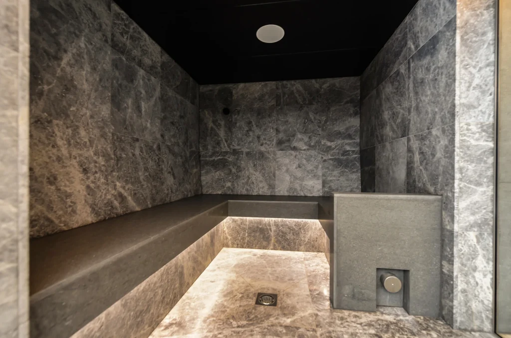 Modern walk-in shower with grey marble tiles and built-in bench