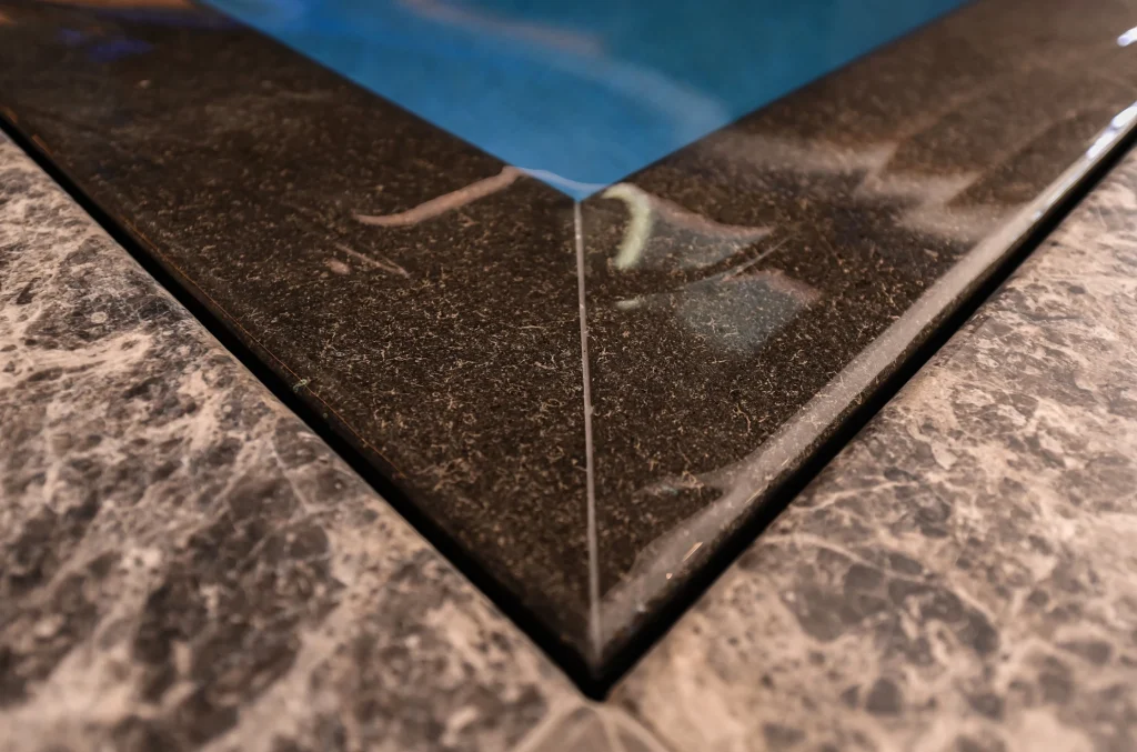 Close-up of pool edge meeting textured concrete deck
